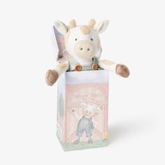 a stuffed cow is sitting in a small box with a tag on it's ear