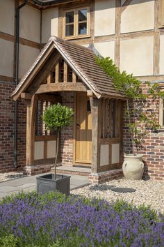 a small wooden building sitting in the middle of a flower garden next to a tall brick building