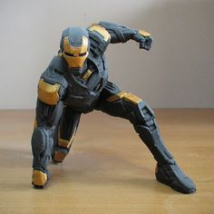 an action figure is posed on a wooden table with a white wall in the background