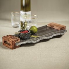 a wooden tray with some fruit on it next to a wine bottle and two glasses