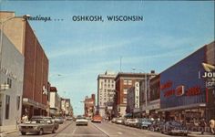 an old postcard shows cars driving down the street in front of shops and businesses