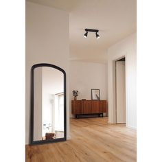 a large mirror sitting on top of a wooden floor next to a wall mounted light