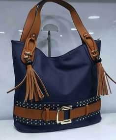 a blue purse with brown handles and tassels on the front, sitting on a white surface