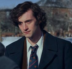 a man with curly hair wearing a suit and tie