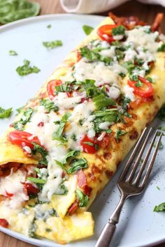 a white plate topped with an omelet covered in cheese and veggies