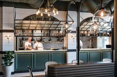 two men are working in the kitchen area of a restaurant with green and white tiles on the walls