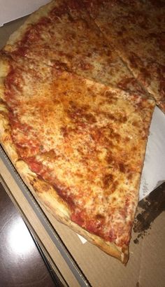 three slices of cheese pizza sitting on top of a cardboard box in front of a window