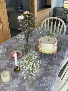 the table is set with flowers, candles and cake for two people to eat at