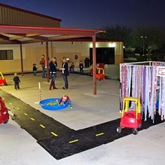 an outdoor play area at night with children playing on the ground and people walking around