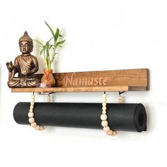 a buddha statue sitting on top of a wooden shelf next to a black yoga mat