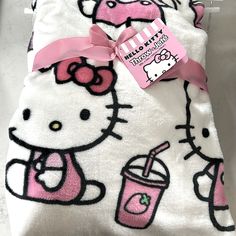 a hello kitty blanket with a pink bow on it's head and a drink in the other hand