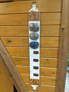 a wooden wall hanging with three different colored buttons on it's side and the letter g