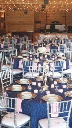 the tables are set with white and blue linens, silverware, and pink napkins