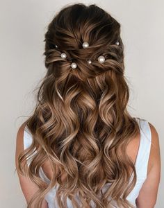 a woman with long wavy hair and pearls in her hair is shown from the back