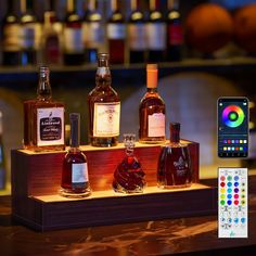 several bottles of liquor are on display with a remote control next to it and an iphone