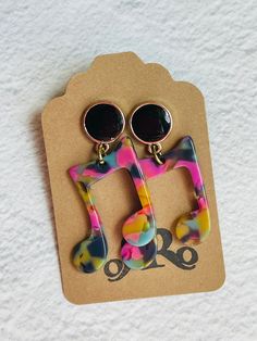 two pairs of colorful earrings sitting on top of a piece of paper