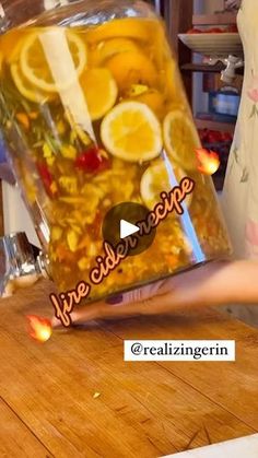 a person holding up a jar full of liquid with lemons and other things in it