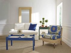 a living room with white furniture and blue accents on the chairs, coffee table and mirror