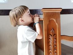 a little boy standing at the top of a wooden table with his hands on it