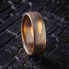 * Price may vary depending on ring size, please inquire with us directly with your needed size for accurate pricing! This beautiful but rugged feeling mokume gane ring features Arn's signature Flow pattern with solid knots, an etched and oxidized finish and a low dome profile. This ring is shown in the Fire metal combination of 14k red gold, 14kt yellow gold and oxidized sterling silver. The pattern is effortless yet intricate, evoking the movements of nature our Flow pattern is inspired by. The solid knots create pools of gold around which the other layers of metal wind like a shining river.  Style: Band  Size Shown: 10.75  Palette: Fire Pattern: Flow with Solid Knots Width: 5mm Finish: Etched & Oxidized Profile: Low Dome *Price does NOT include stones and setting fees* All Arn Krebs Moku Rustic Wedding Band, Mokume Gane Ring, Rustic Wedding Bands, Mokume Gane, Oxidized Sterling Silver, The Fire, Gold Style, Silver Band, Red Gold