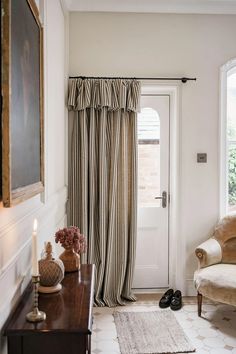 a living room filled with furniture and a window covered in drapes next to a white door