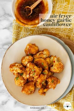 a white plate topped with fried food next to a bowl of honey garlic cauliflower