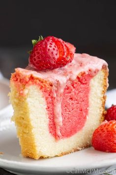 a slice of strawberry cake on a plate with two strawberries