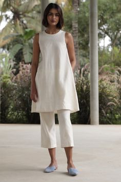 An elegant co-ord set in Lush Handwoven Chanderi silk. Sleeveless tunic with a close round neck. Back button fastening. In-seam pockets. Fully lined. Can be worn separately as a dress. Paired with easy, crop pants. Elasticated waist. In-seam pockets. Fully lined. Tip: Wear them together or mix and match with other styles in your wardrobe. Garment Measurements in inches: TUNIC XS S M L XL CHEST 34 35.5 37 38.5 40 WAIST 41 42.5 44 45.5 47 HIP 49 50.5 52 53.5 55 LENGTH 37 37.25 37.5 37.75 38 SHOULD Co Ords Outfits, Casual Indian Fashion, Coord Set, Easy Outfit, Pakistani Dress, Shirts Design, Stylish Dress Designs, Sleeveless Tunic, Suit Designs