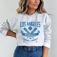 "This Los Angeles Baseball Apparel is the perfect way to cheer on the home team this season. Ideal for game day, tailgates or everyday wear. Makes a great gift for any fan. SHIRT DETAILS Bella Canvas Unisex - Solid colors: 100% Cotton. - Heather colors: 52% Cotton + 48% Polyester - Runs true to size. (For looser or oversized fit consider going up a size or 2. See photos for size chart.) SWEATSHIRT & HOODIE DETAILS Gildan Heavy Blend Unisex - 50% Cotton + 50 Polyester - Runs true to size. (For looser or oversized fit consider going up a size or 2. See photos for size chart.) CARE INSTRUCTIONS Do not dryclean; Machine wash: cold (max 30C or 90F); Non-chlorine: bleach as needed; Tumble dry: low heat; Iron or steam: medium heat. Wash, dry and iron inside out. MORE DESIGNS AVAILABLE https://www Sports Sweatshirt With Logo Print In Athletic Heather, Athletic Heather Sweatshirt With Logo For Sports, Athletic Heather Crew Neck Hoodie For Sports Season, Crew Neck Hoodie For Sports Events, Sporty Hoodie In Athletic Heather With Crew Neck, Team Spirit Letter Print Crew Neck Hoodie, Athletic Heather Sweatshirt For Sports Fans, Athletic Heather Sportswear Sweatshirt For Sports Season, Baseball Season Fan Merchandise Sweatshirt