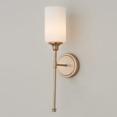 a wall light with a white glass shade on it's arm and the bulb turned off