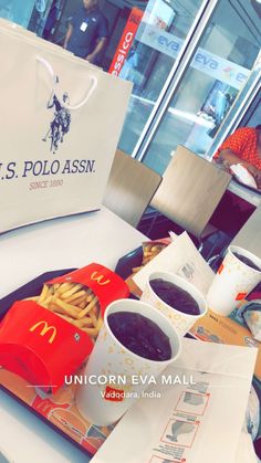 a table topped with french fries and hotdogs next to a paper bag filled with ketchup