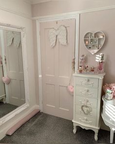 a white dresser sitting next to a mirror in a room with pink walls and furniture