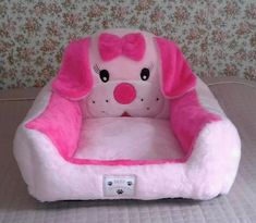 a pink dog bed with a bow on it's head and paws in the front