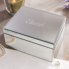 a silver jewelry box sitting on top of a table next to a candle and flowers