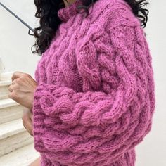 a woman in a pink sweater holding an umbrella