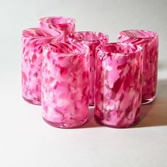 four pink vases sitting next to each other on a white surface