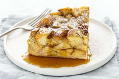 a white plate topped with a piece of cake covered in caramel sauce and powdered sugar