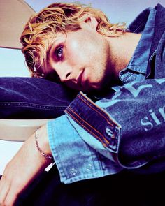 a man laying on top of a white toilet next to a blue shirt and jeans