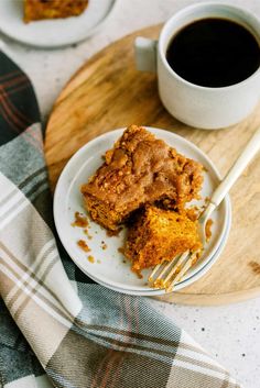 a piece of cake on a plate next to a cup of coffee and a fork