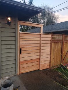 a large wooden gate in front of a house with a light on it's side