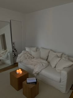 a living room with a white couch and two candles on the coffee table in front of it