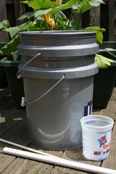 the bucket is sitting on the deck next to the flower pot