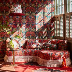 the sun shines through the windows onto a colorfully decorated couch and ottoman in an otherwise empty room