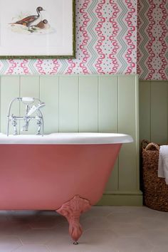 a pink bath tub sitting next to a painting on the wall