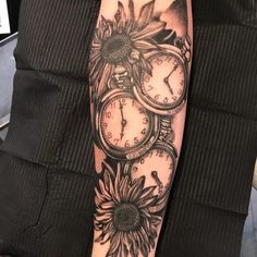 a person with a tattoo on their arm has clocks and sunflowers around them