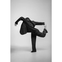 a man in a suit doing a handstand on one leg with his legs spread out