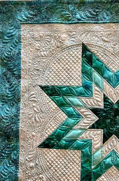 a green and white quilted wall hanging with an intricate design on the front side