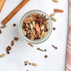 an overhead view of a glass jar filled with nuts, cinnamons and star anise