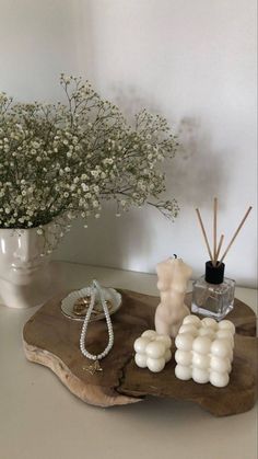 a vase with flowers and candles sitting on a wooden tray next to a candle holder