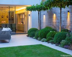 an outdoor living area is lit up with lights and greenery in the foreground